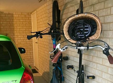 Dos bicicletas aparcadas en Steadyracks, compartiendo una pequeña plaza de garaje con un coche.